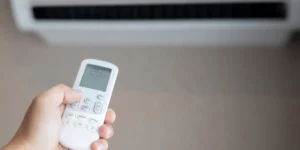 A person is adjusting the settings on their air conditioner with a remote control